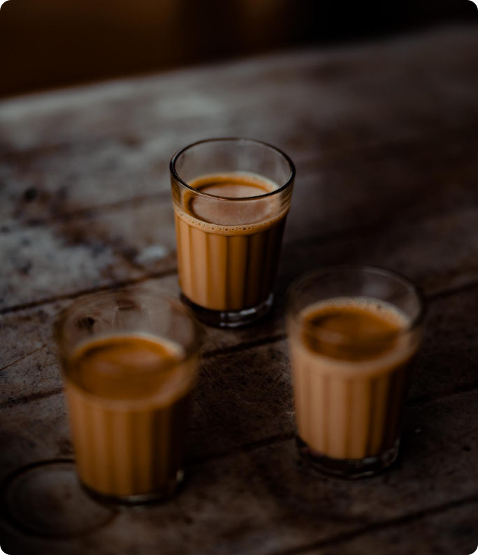 Three glasses of chai on a wooden table